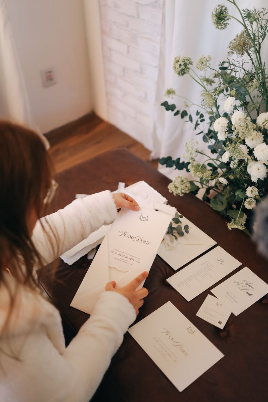 Mãos sobre convites de papel algodão no ateliê Espoir