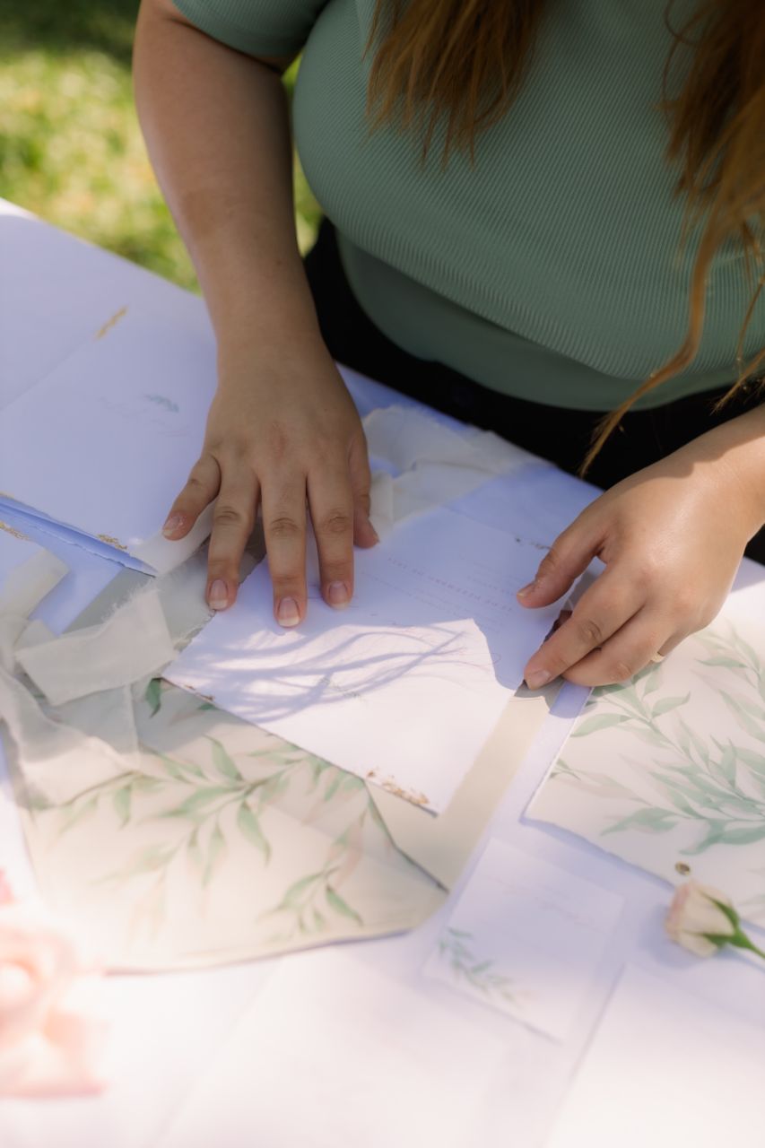 Detalhe de mãos, papel artesanal e folhagem ao ar livre